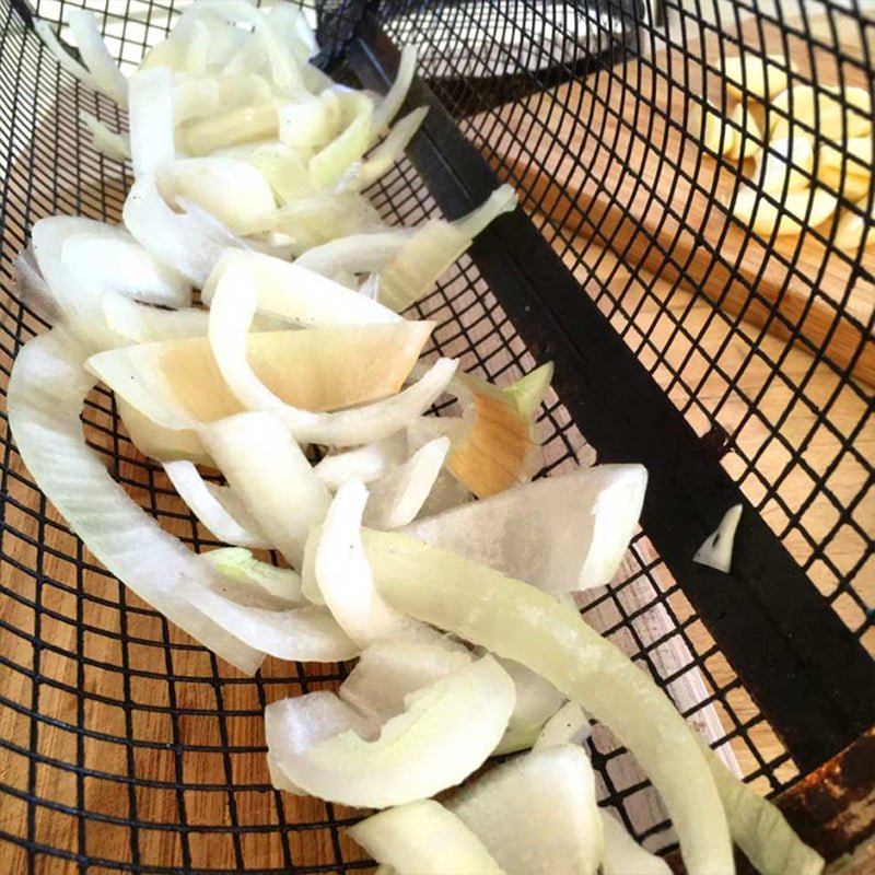 Detail van witte uienringen in een barbecuemand