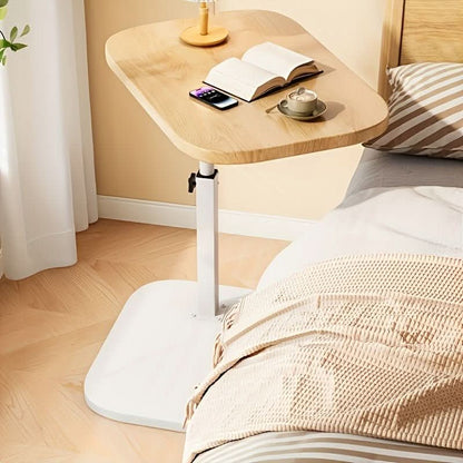 Lichte bijzettafel met witte voet naast een bed