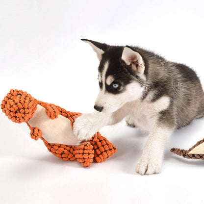 Puppy speelt met een oranje pluche dinosaurus
