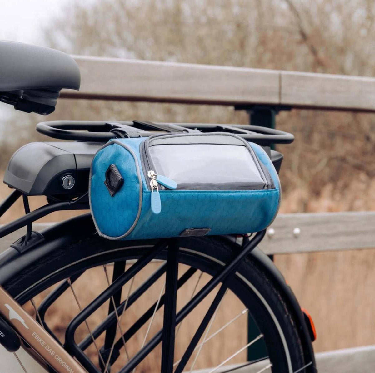 Blauwe fietstas met telefoonvenster aan een bagagedrager