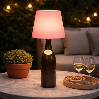 Roze fleslamp op een donkere fles op een buitentafel