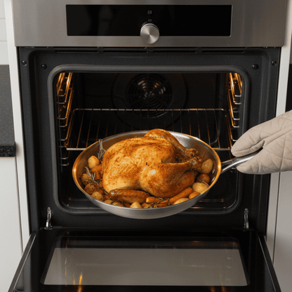 Koekenpan met gebraden kip bij een open oven
