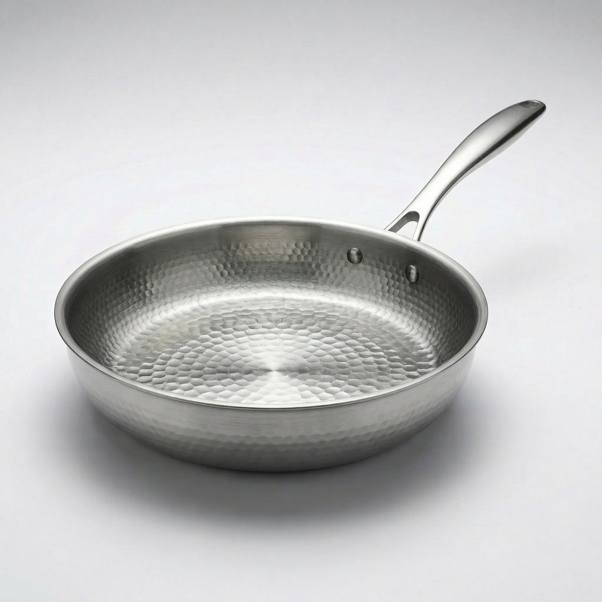 Zilverkleurige koekenpan met metalen steel schuin van boven