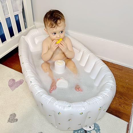 Kind zit in een wit opblaasbaar babybadje met print