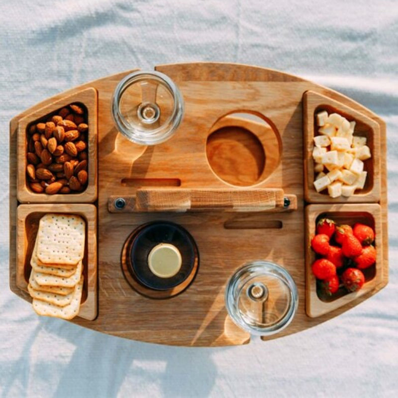 Bovenaanzicht van houten picknicktafel met glazen en hapjes