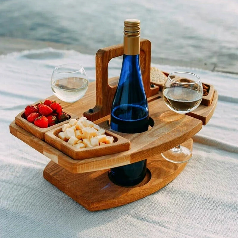 Houten picknicktafel met fles, glazen en hapjes op een kleed