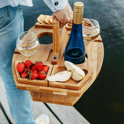 Persoon draagt een houten picknicktafel met fles, glazen en hapjes