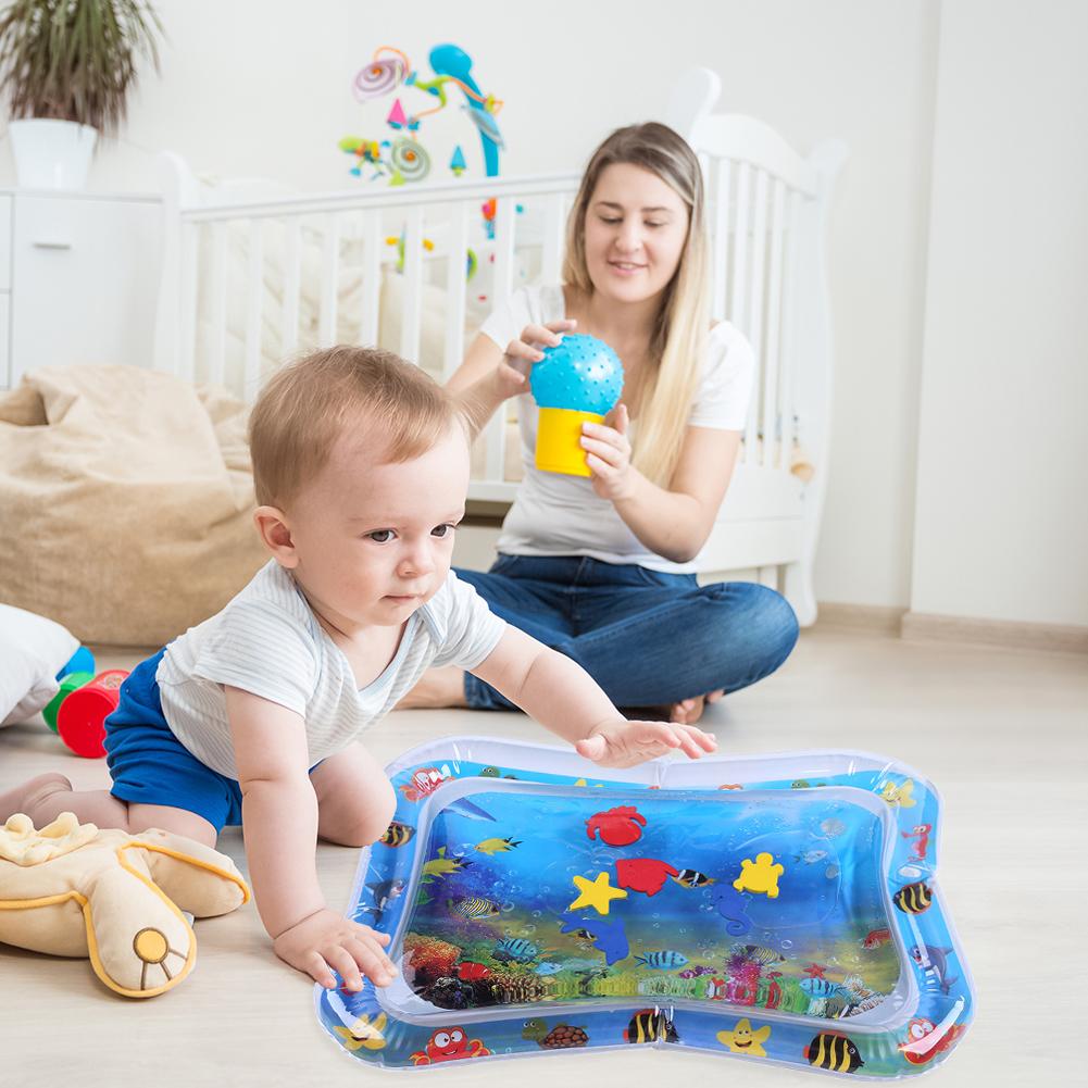 Kind op een waterspeelmat naast een volwassene in de woonkamer